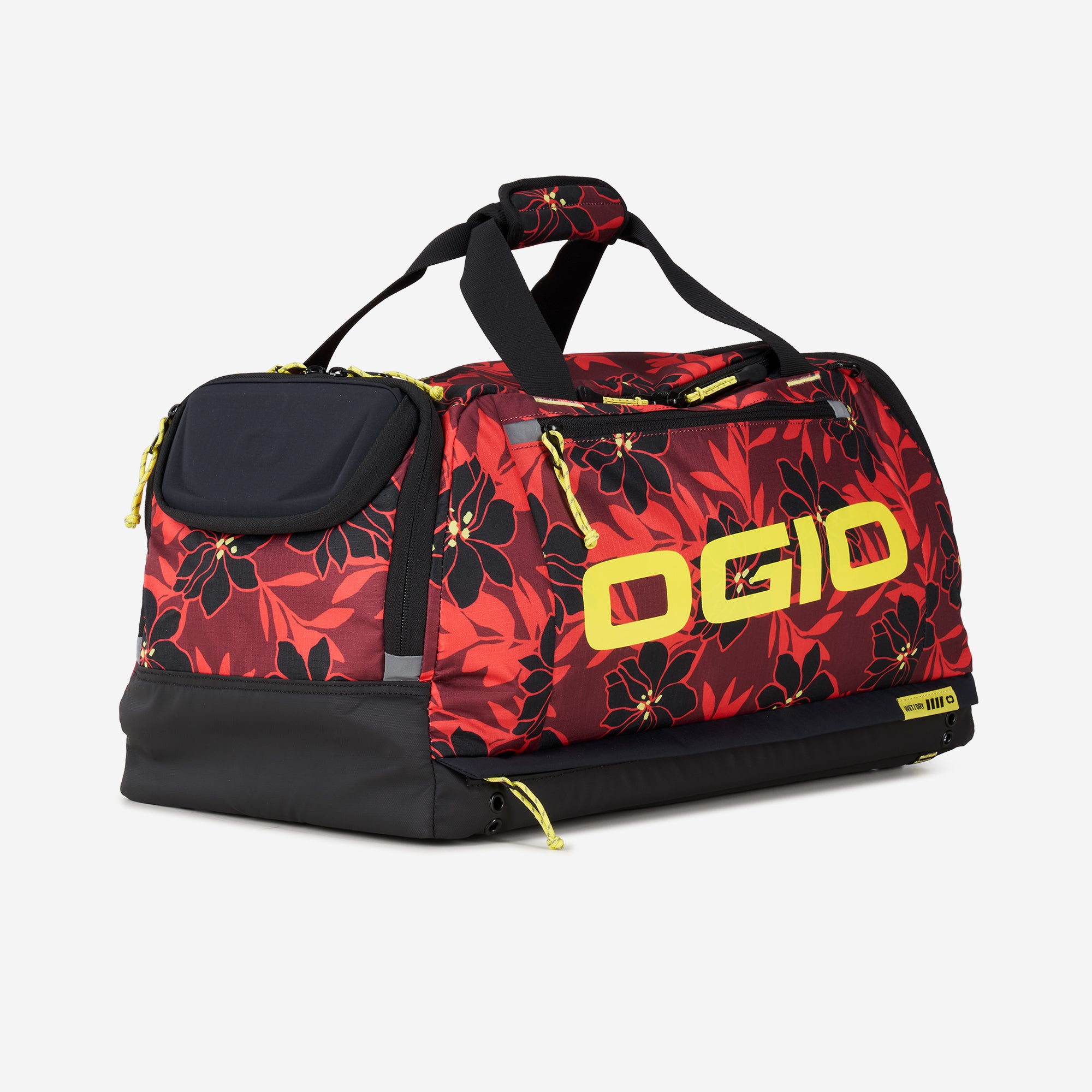 A red duffel bag with a floral pattern and black accents, featuring multiple compartments and the brand name 'OGIO' displayed prominently.